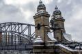 Historische Brücke mit steinernen Türmen und eisernen Bögen, teilweise mit Schnee bedeckt.