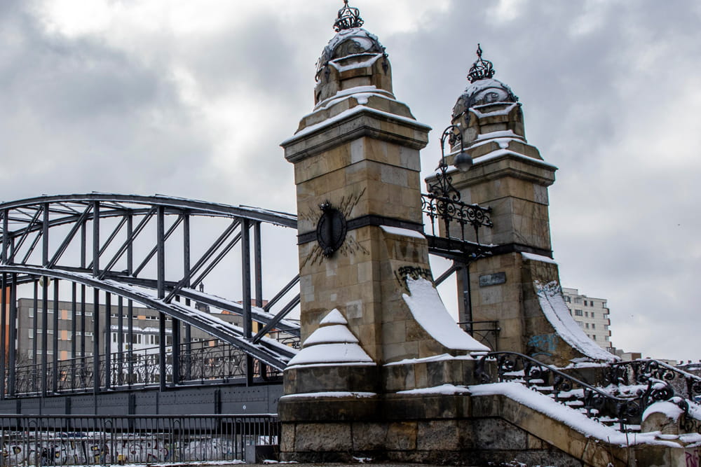 Privatdetektiv Berlin – Charlottenburg und Wilmersdorf Historische Brücke mit steinernen Türmen und eisernen Bögen, teilweise mit Schnee bedeckt.